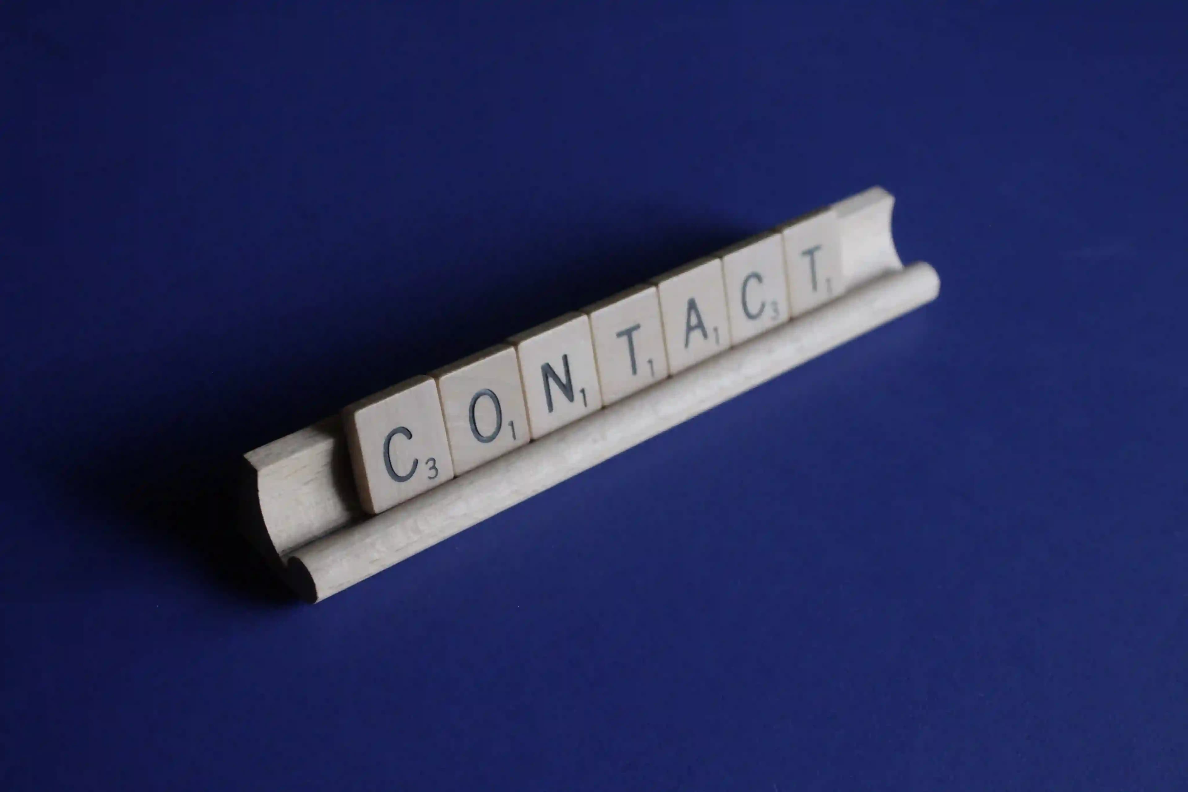 The word contact spelled out with scrabble tiles